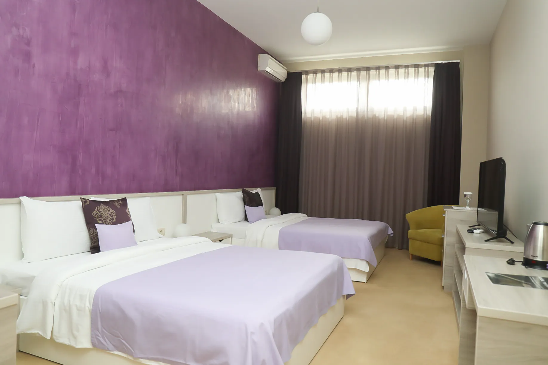 The Deluxe Family Room at Coconut, with three beds against a plum-coloured wall
