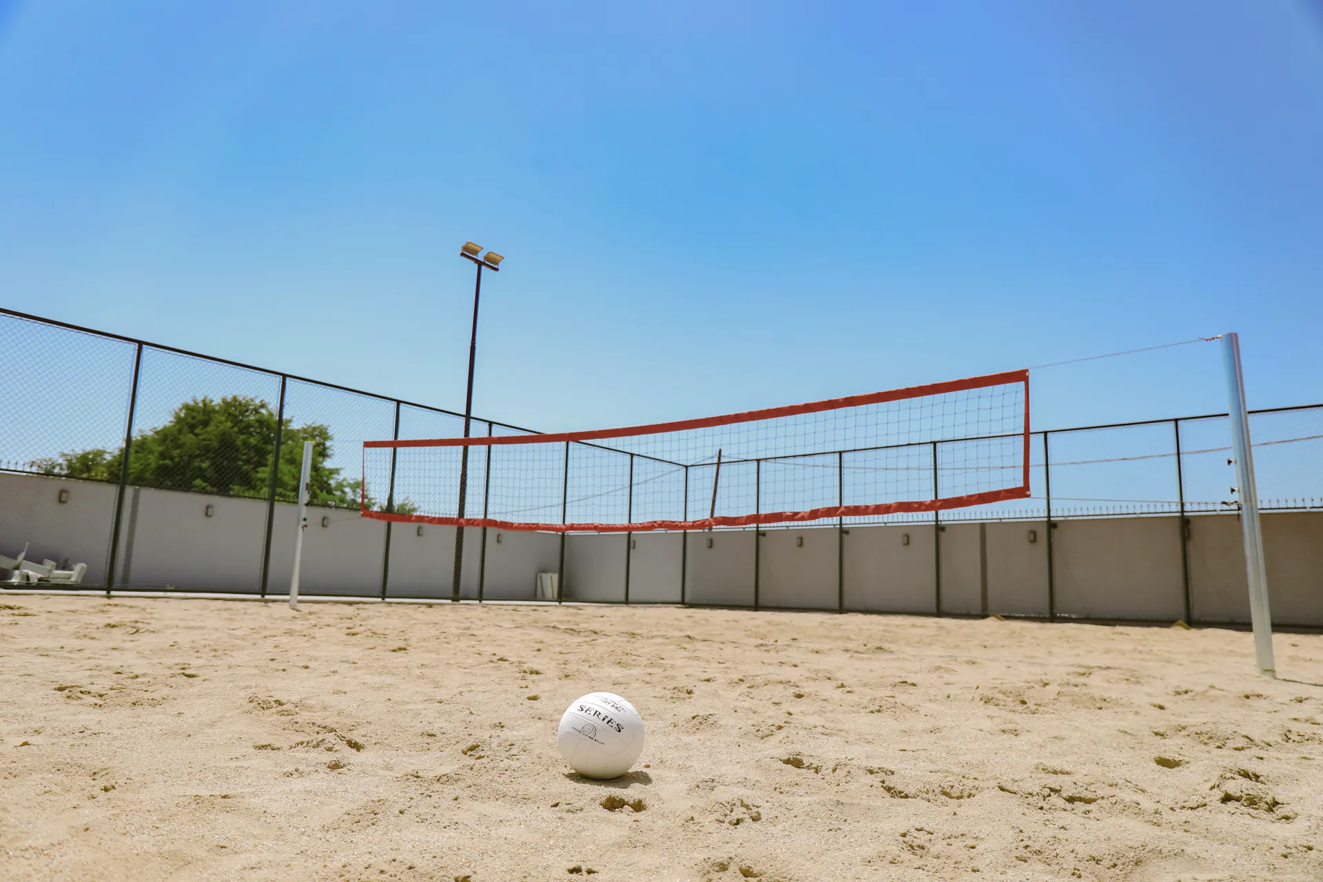 The sand volleyball court at Coconut, with the net up and a ball on the sand
